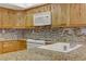 Close-up of kitchen with granite countertops, mosaic backsplash, stainless steel sink, and white appliances at 7385 Mission Hills Dr, Las Vegas, NV 89113