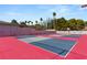 Multi-colored tennis court with surrounding landscaping and fencing for an active lifestyle at 7440 Edna Ave, Las Vegas, NV 89117