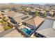 Aerial view showcases backyard pool and patio area with surrounding houses and desert mountain backdrop at 781 Drammatico Pl, Henderson, NV 89011