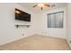 Cozy bedroom with carpet, ceiling fan, mounted TV, and a window with vertical blinds at 97 Parker Ranch Dr, Henderson, NV 89012