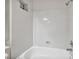 Clean white bathroom with a full bathtub, shower head, and small window at 1562 Pimlico Hills St, Henderson, NV 89014