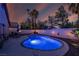Inviting backyard pool with an illuminated water feature, surrounded by lush greenery and palm trees at dusk at 254 Camelback Ridge Ave, Henderson, NV 89012