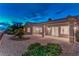 The stucco exterior of this home includes a covered patio and a desert landscaped backyard at twilight at 2747 White Sage Dr, Henderson, NV 89052