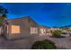 Dusk falls on this desert landscaped backyard; sliding doors enter into the house under the covered patio at 2747 White Sage Dr, Henderson, NV 89052