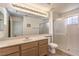 Bright bathroom with large mirror, spacious vanity, shower with glass door, and neutral tile flooring at 2747 White Sage Dr, Henderson, NV 89052
