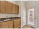 This laundry room features wooden cabinets, a granite countertop, a sink, and a door to the outside at 2747 White Sage Dr, Henderson, NV 89052