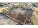 View of the lot, surrounded by a chain-link fence, and with dirt, trees and desert landscape at 3051 S Rainbow Ave, Pahrump, NV 89048