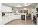 Bright kitchen featuring white cabinets, hardwood floors, neutral walls, stone countertops, and modern appliances at 3051 S Rainbow Ave, Pahrump, NV 89048