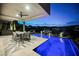 Outdoor patio with a swimming pool, dining table, and city views at twilight at 38 Promenade Isle Ln, Henderson, NV 89011