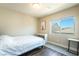 A simple bedroom is enhanced by wood-look floors, a neutral color palette, and a large window at 7029 Parrot Bay Way, Las Vegas, NV 89118