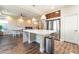 Modern kitchen and living area with stainless steel appliances, an island with marble countertop, and hardwood floors at 7029 Parrot Bay Way, Las Vegas, NV 89118