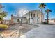 Two-story home featuring a grand entrance, palm trees, and rock landscaping at 7477 Ullom Dr, Las Vegas, NV 89139