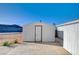 A small, white outbuilding with a single door and concrete pad, that could be used for storage at 7477 Ullom Dr, Las Vegas, NV 89139