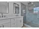 Bathroom featuring double sinks, a marble countertop, and a tiled walk-in shower with a glass door at 7640 Sea Wind Dr, Las Vegas, NV 89128