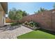 Beautiful backyard features artificial grass, stone landscaping, and brick-paved patio area at 10057 Regency Canyon Way, Las Vegas, NV 89148