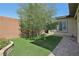 Well-maintained backyard with artificial grass, a tree, and brick-paved areas at 10057 Regency Canyon Way, Las Vegas, NV 89148
