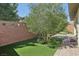 Manicured backyard with artificial grass, a tree, and brick-paved areas at 10057 Regency Canyon Way, Las Vegas, NV 89148