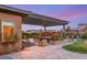 Stunning backyard features a covered patio with lounge area and hot tub surrounded by lush landscaping and pavers at 10179 Emerald Sunset Ct, Las Vegas, NV 89148