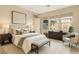 Staged bedroom with large bed, art and view to the exterior through multiple windows at 10179 Emerald Sunset Ct, Las Vegas, NV 89148