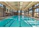 An indoor swimming pool features clear blue water, ample natural light, and a spacious deck with comfortable lounge chairs at 10179 Emerald Sunset Ct, Las Vegas, NV 89148