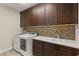 Laundry room with a washer, dryer, upper cabinets and tile backsplash at 10179 Emerald Sunset Ct, Las Vegas, NV 89148