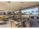 Covered outdoor patio with lounge seating, dining tables, and stainless steel grill at 10179 Emerald Sunset Ct, Las Vegas, NV 89148