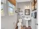 Cozy half bathroom with pedestal sink, decorative shelving, and natural light from the window at 10313 Aragon Crown Rd, Las Vegas, NV 89135