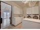 Bright laundry room with white cabinets, sink, washer, and dryer, with view to office space at 1704 Tangiers Dr, Henderson, NV 89012
