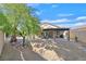A private backyard with a covered patio, desert landscaping, and a mature shade tree at 301 Treehouse Ct, Henderson, NV 89012