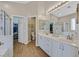 Bright bathroom featuring double vanity, soaking tub, and glass enclosed shower and walk in closet at 301 Treehouse Ct, Henderson, NV 89012