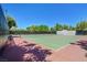 Community tennis court with red and green surface, net, and benches for relaxing at 301 Treehouse Ct, Henderson, NV 89012