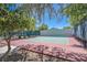 Community tennis court with red and green surface, net, and mature trees providing shade at 301 Treehouse Ct, Henderson, NV 89012