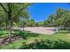 Community volleyball court with sand surface, green grass, mature trees, and lush greenery at 301 Treehouse Ct, Henderson, NV 89012