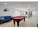 Open concept game room with a pool table, blue sofa, and a view of the kitchen and breakfast bar at 3431 Iberia St, Las Vegas, NV 89146