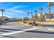 Landscaped community entrance with palm trees, manicured shrubbery, and attractive road layout under a blue sky at 351 Dandelion Brook Ct Ct, Las Vegas, NV 89148