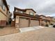 Attractive two-car garage with stone accents and a charming tan exterior elevation and brick paved driveway at 7719 Windy Meadow Ave, Las Vegas, NV 89178