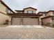 Attractive two-car garage with stone accents and a charming tan exterior elevation and brick paved driveway at 7719 Windy Meadow Ave, Las Vegas, NV 89178