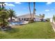 Expansive backyard with a sparkling pool, lush green grass, and mature palm trees at 8290 Gagnier Blvd, Las Vegas, NV 89113