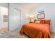 Inviting bedroom with orange bedding, plush carpet, a mirrored sliding-door closet, and ample natural light at 905 Belleforte Ln, Las Vegas, NV 89138