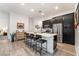 Modern kitchen island with seating, sleek dark cabinetry, stainless steel appliances, and wood-look tile flooring at 905 Belleforte Ln, Las Vegas, NV 89138