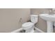 Powder room featuring modern fixtures including a pedestal sink and white toilet on a wood-look floor at 12836 Alcores St, Las Vegas, NV 89141