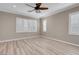 Bedroom features wood-look floors, white trim, ceiling fan, and natural light from shuttered windows at 12836 Alcores St, Las Vegas, NV 89141