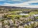 An aerial view of a community featuring a golf course, lake, mountains in the distance, and a variety of home styles at 1477 Foothills Village Dr, Henderson, NV 89012