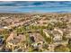 An aerial view capturing a neighborhood nestled among mature trees, featuring mountains in the distance at 1477 Foothills Village Dr, Henderson, NV 89012