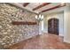 Elegant dining room with rustic stone wall, beamed ceiling, and wrought iron chandelier at 1477 Foothills Village Dr, Henderson, NV 89012