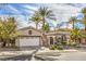 Charming single-story home with a well-manicured yard, complemented by swaying palm trees and a beautiful driveway at 1477 Foothills Village Dr, Henderson, NV 89012