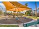 Community playground shaded with canopy, featuring play structures, rideable toys, and park benches for relaxation at 1477 Foothills Village Dr, Henderson, NV 89012