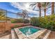 A cozy and luxurious inset pool with stone trim is surrounded by lush landscaping and a wrought-iron fence at 1477 Foothills Village Dr, Henderson, NV 89012