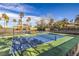Well-maintained tennis court with palm trees, offering a recreational amenity for residents under a clear blue sky at 1477 Foothills Village Dr, Henderson, NV 89012