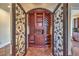 Charming wine room with custom shelving and cabinetry, enclosed by decorative wrought iron doors at 1477 Foothills Village Dr, Henderson, NV 89012
